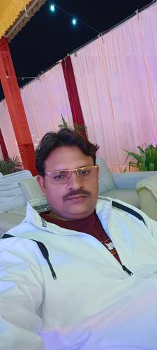 a man with glasses laying in a hospital bed at Mahajan Palace and lodge in Naini