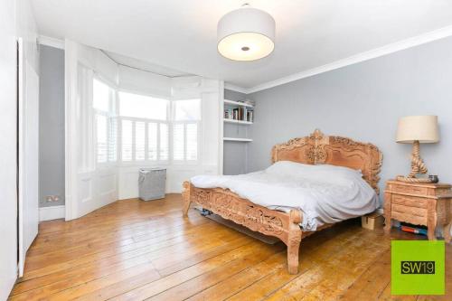 a white bedroom with a bed and a wooden floor at Modern 2 Bedroom with Free Parking & near Tube in London