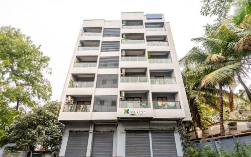 a tall white building with windows and palm trees at Treebo Trend Raana Encore - Near Magarpatta in Pune