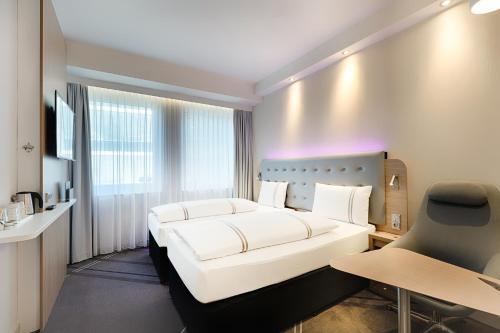una camera d'albergo con letto bianco e scrivania di Premier Inn Lindau a Lindau