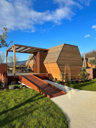 a building with a wooden roof on a grass field at Glamping Alvearium Alturis in Gagliano