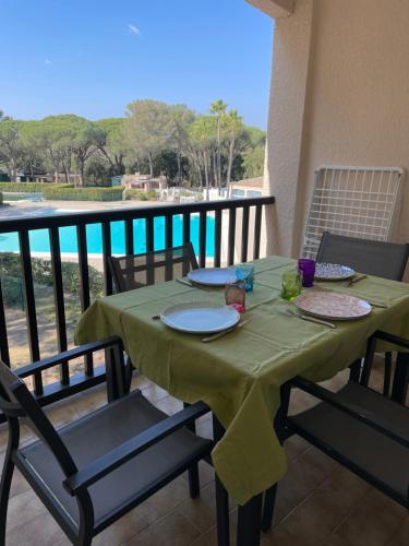 d'une table verte avec des chaises et des assiettes sur un balcon dans l'établissement Studio cabine vu sur piscine, à Valescure