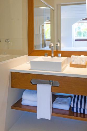a bathroom with a sink and a mirror and towels at Le Relais La Borie in Búzios