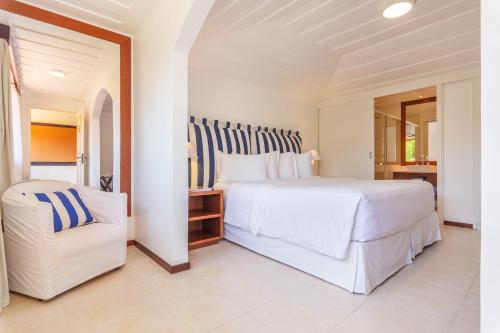 a bedroom with a large white bed and a chair at Le Relais La Borie in Búzios