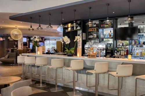 un bar en un restaurante con taburetes blancos en Novotel Paris Centre Bercy, en París