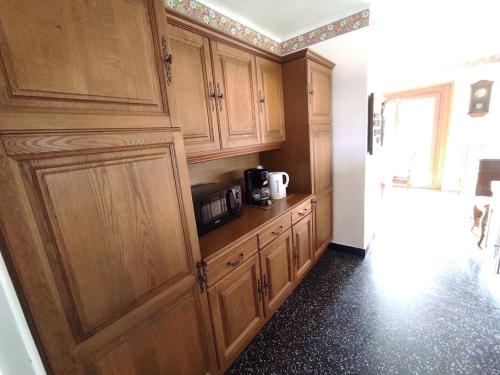 a kitchen with wooden cabinets and a microwave at Appartement indépendant dans une maison calme in Amancy
