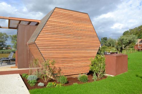 a small house with a wooden wall in a yard at Glamping Alvearium Alturis in Gagliano