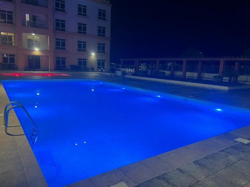 a blue swimming pool in front of a building at night at هافانا المارينا Apartment in King Abdullah Economic City