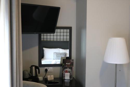 a bedroom with a bed and a flat screen tv at Norfolk Arms in Glossop