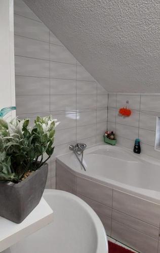 a white bathroom with a tub and a potted plant at Kuća za odmor Boki in Gospić
