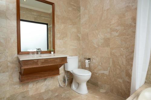 a bathroom with a toilet and a mirror at Girihill Farmhouse in Munduk