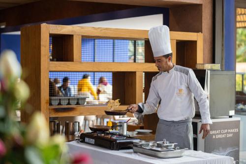 a chef standing in a kitchen preparing food at Al Maaden Villa Hotel & Spa in Marrakech