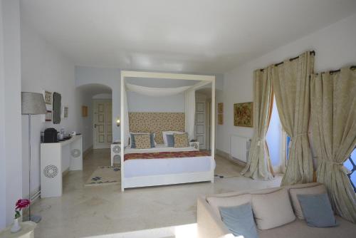 a white bedroom with a bed and a large mirror at La Demeure in Sidi Bou Saïd