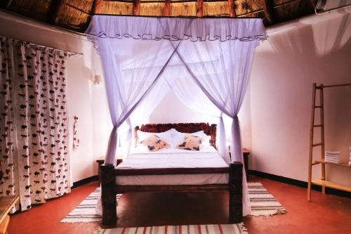 a bedroom with a canopy bed with blue curtains at Acaki Lodge in Kitgum