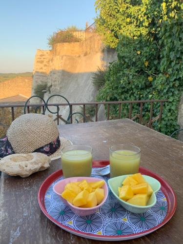 a table with a plate of fruit and two glasses of orange juice at La rose du vent in Saint-Pons-de-Mauchiens