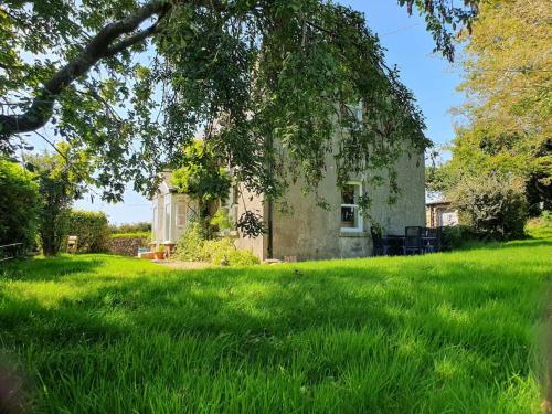 a house in the middle of a field of green grass at Knockanree Cottage-Quiet, tranquil country hideaway in Avoca