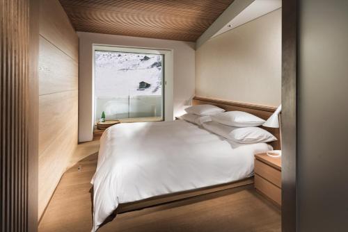 um quarto com uma grande cama branca e uma janela em House of Architects em Vals