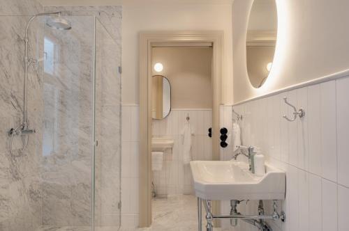 biała łazienka z umywalką i prysznicem w obiekcie Clas på Hörnet w Sztokholmie