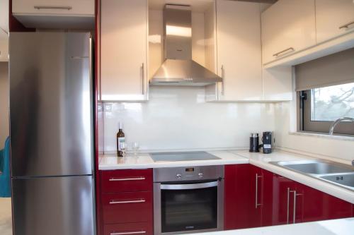 eine Küche mit roten Schränken und einem Kühlschrank aus Edelstahl in der Unterkunft Blue Diamond in Chrani