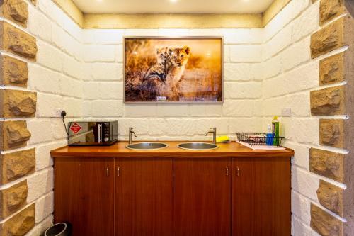a bathroom with a sink and a painting of a lion at The Jungle Oasis with heated pool in Nairobi