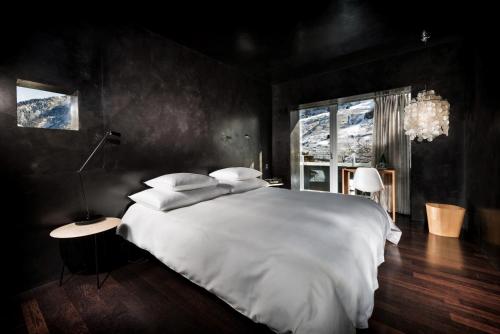 a bedroom with a large white bed and a window at House of Architects in Vals