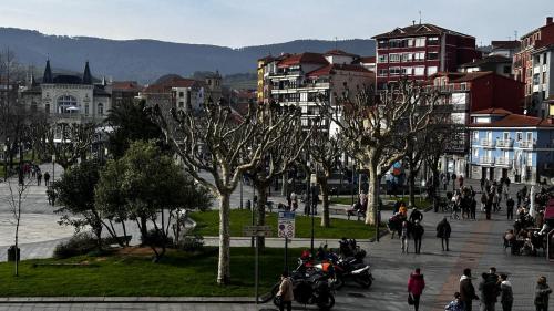 a group of people walking and riding motorcycles on a city street at Apartamento Etxe Morea, Casco Histórico in Bermeo