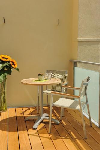 a table and a chair and a table and a vase with flowers at Hotel Ratsstuben in Lindau