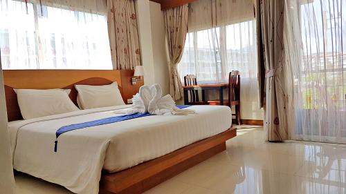 sypialnia z dużym łóżkiem z białą pościelą i oknami w obiekcie Green Harbor Hotel & Service Apartment w Patong Beach