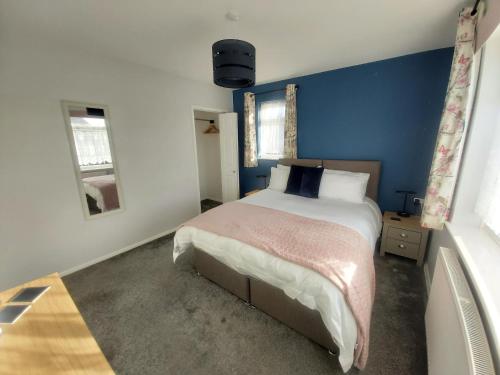 Totland的住宿－Corner Cottage，一间卧室配有一张带蓝色墙壁的大床