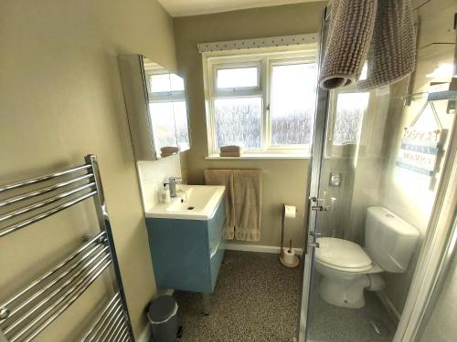 a bathroom with a sink and a toilet and a window at Corner Cottage in Totland