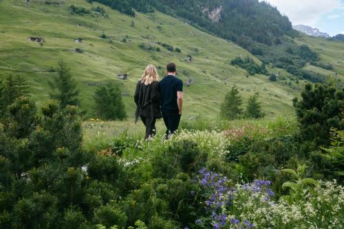a man and woman walking through a field of flowers at House of Architects in Vals