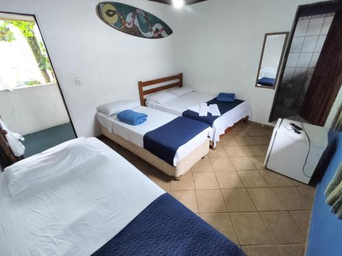 um quarto com duas camas e um espelho em Pousada Boiçucanga a 30m da praia em Boicucanga