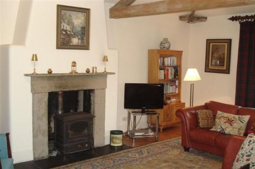 a living room with a fireplace and a tv at The Coach House at Bryngwyn Hall in Llanfyllin
