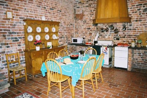 a kitchen with a table with chairs and a brick wall at The Coach House at Bryngwyn Hall in Llanfyllin