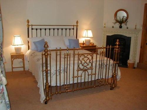a bed in a bedroom with two lamps and a fireplace at The Coach House at Bryngwyn Hall in Llanfyllin