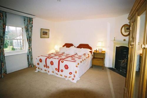 a bedroom with a bed with a red and white blanket at The Coach House at Bryngwyn Hall in Llanfyllin