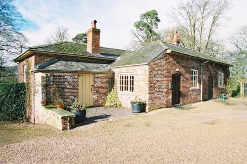 an old brick house with a garage in a yard at The Coach House at Bryngwyn Hall in Llanfyllin