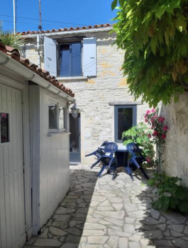 un patio avec une table et des chaises devant un bâtiment dans l'établissement Lovely cosy house, à La Flotte