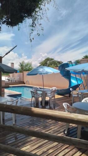 a pool with tables and umbrellas on a deck at Pousada Recanto Passarela in Aparecida