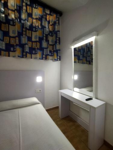 a bedroom with a white bed and a mirror at Hotel Casa del Sol in Puerto de la Cruz