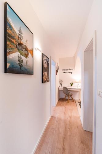 a hallway with a white wall with paintings on it at Central Athena Studio - Inima Pieței Unirii - By OpenHouse apartments in Timişoara