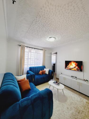 un salon avec un canapé bleu et une télévision dans l'établissement Queen homes, à Ruiru