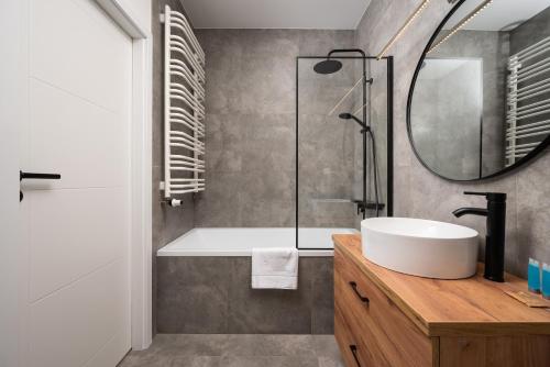 a bathroom with a tub and a sink and a mirror at High Wilanów Modern Apartment in Warsaw