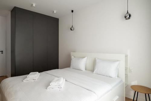 a bedroom with a white bed with two towels on it at High Wilanów Modern Apartment in Warsaw