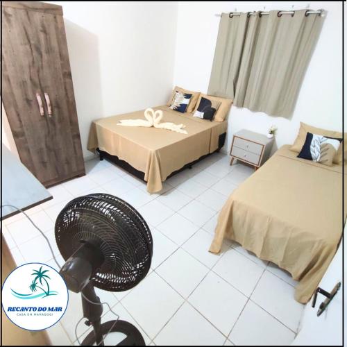 a room with two beds and a fan in it at Recanto do Mar- Casa em Maragogi in Maragogi