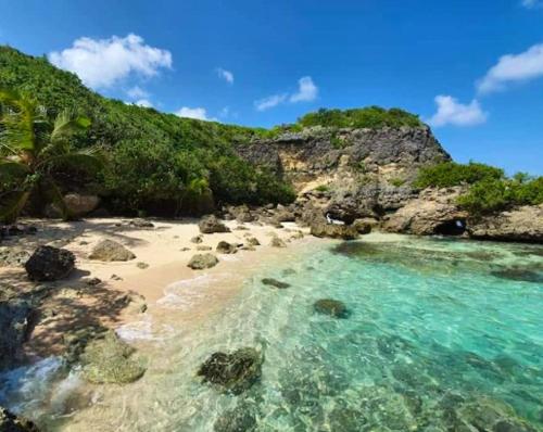 a beach with blue water and rocks and a mountain at Maison de 3 chambres avec jardin clos et wifi a Anse Bertrand in Anse-Bertrand