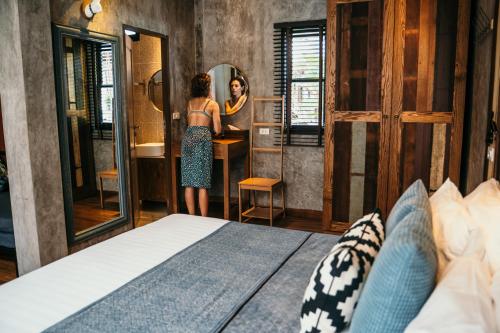 a woman standing in front of a mirror in a bedroom at Sand in My Shoes Beach Loft in Thong Nai Pan Noi