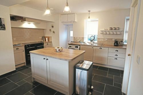 a kitchen with white cabinets and a wooden counter top at Hen-Dy, Frongaled in Dyffryn