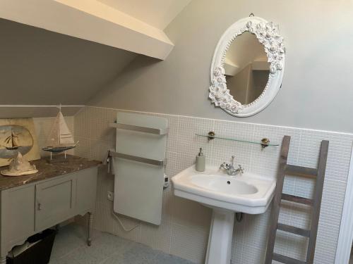 baño con lavabo y espejo en la pared en Le Bourg, en Asnières-en-Bessin