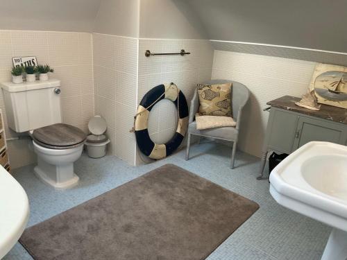 La salle de bains est pourvue de toilettes, d'une chaise et d'un lavabo. dans l'établissement Le Bourg, à Asnières-en-Bessin